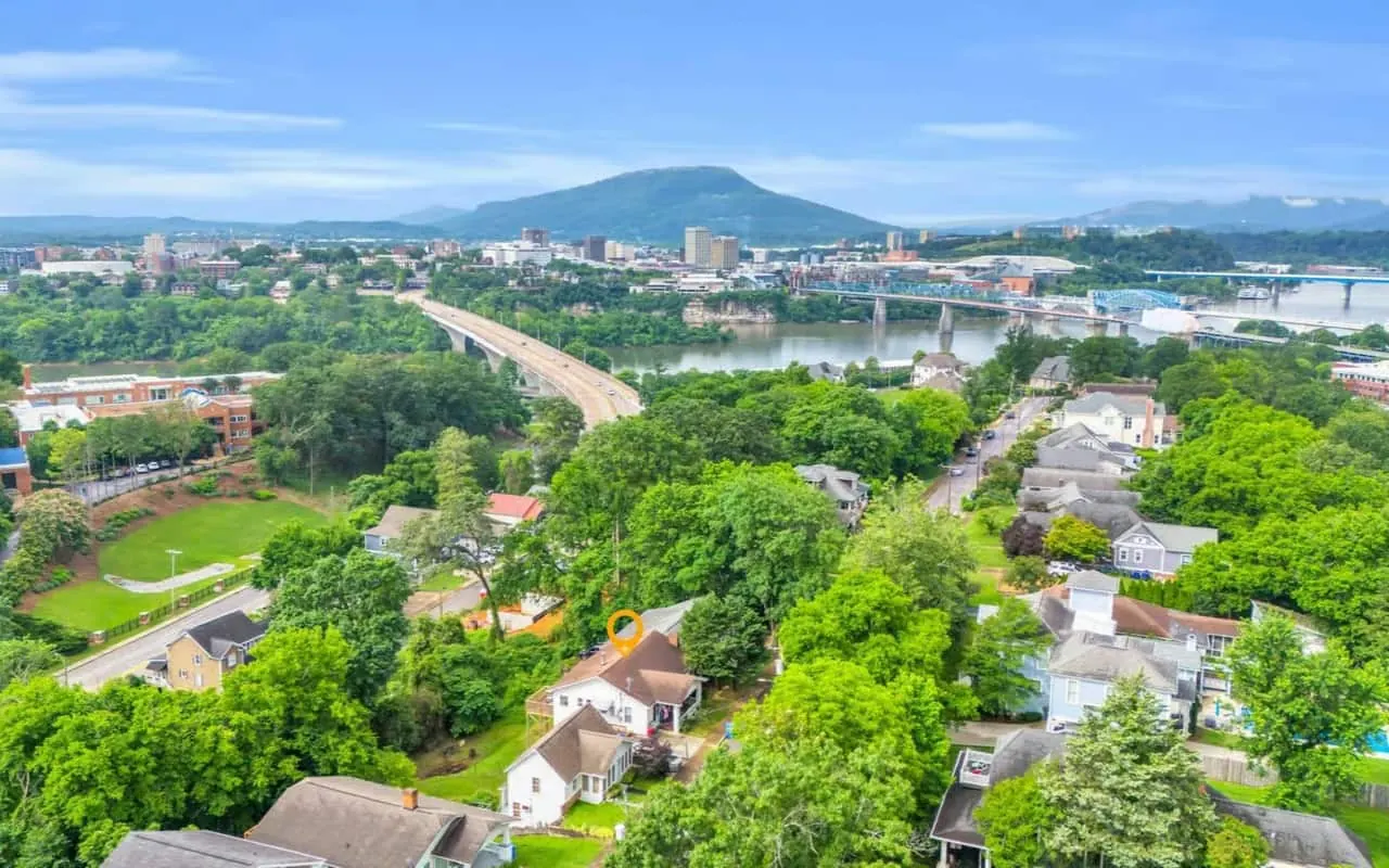 Aerial view of a tree-lined residential neighborhood, with the Tennessee River, a city skyline and a mountain ridge in the distance