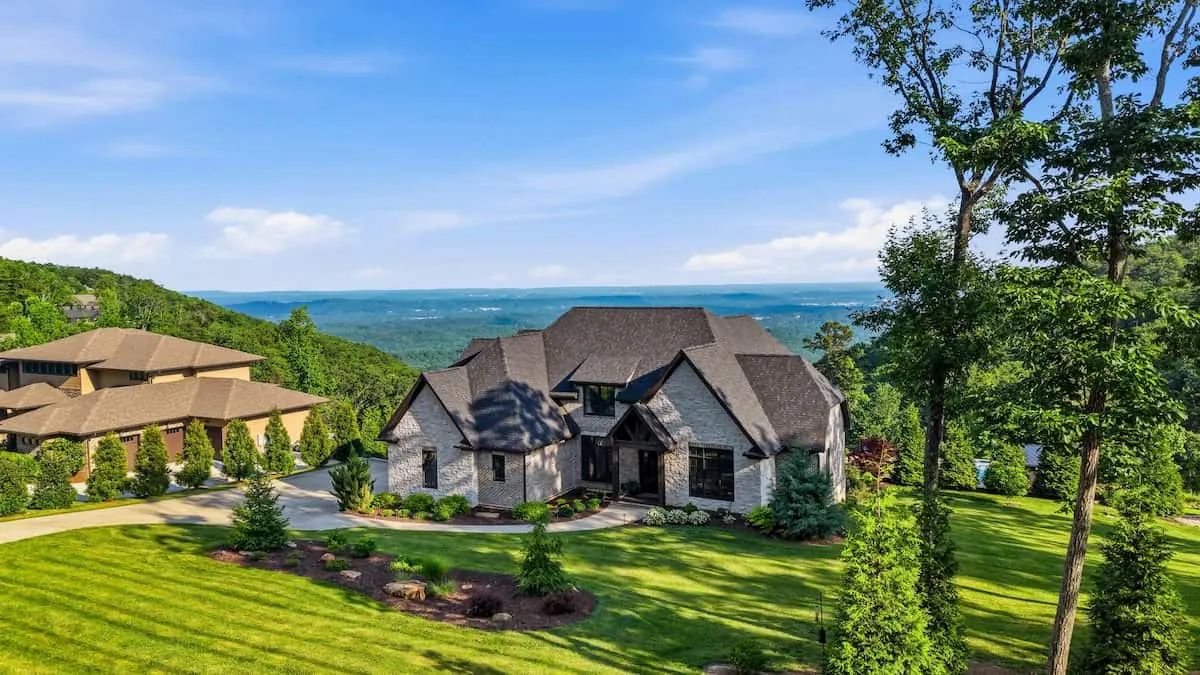 A stone-faced home on a landscaped ridgetop lot on Signal Mountain, with wooded valleys stretching to the horizon behind it