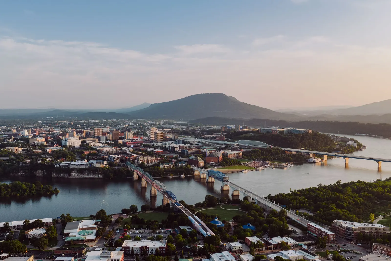 Chattanooga at golden hour, with the Tennessee River, its bridges and Lookout Mountain under a soft evening sky.