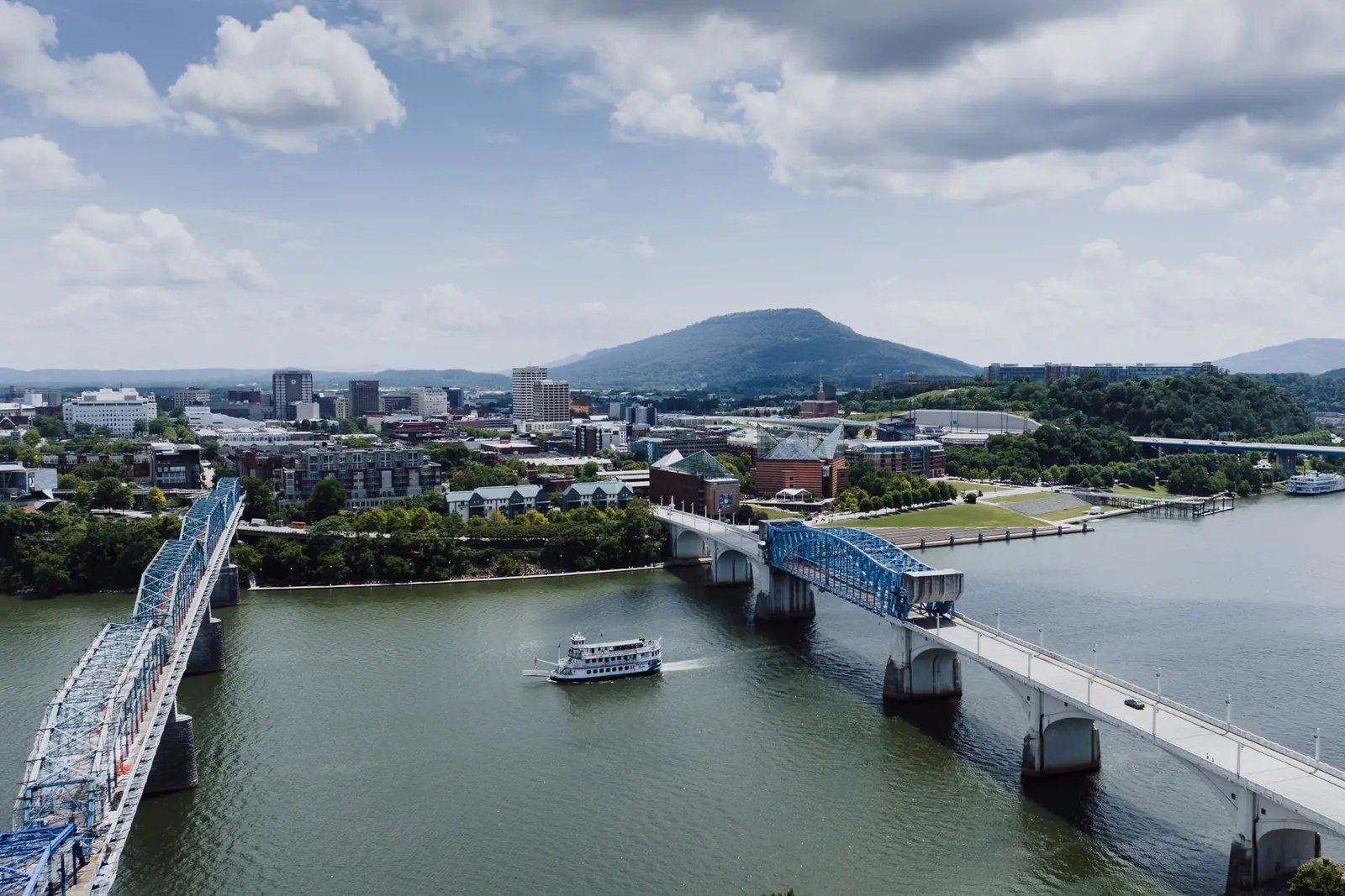 Downtown Chattanooga on the Tennessee River, with the blue Walnut Street Bridge, a riverboat and Lookout Mountain in the distance.